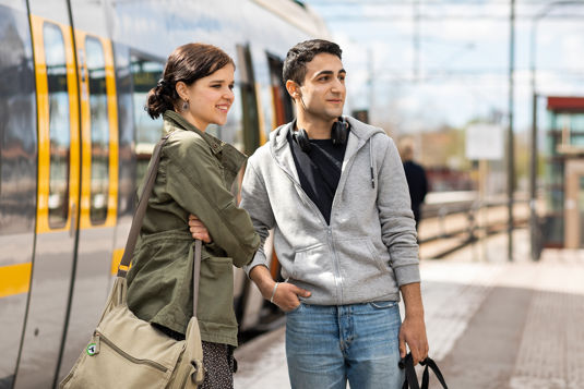 Två ungdomar väntar på tåget vid perrongen